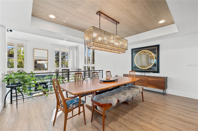 dining space featuring a tray ceiling, light hardwood / wood-style floors, and wooden ceiling