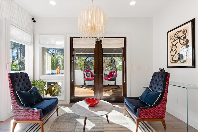 living area featuring french doors, wood-type flooring, and a notable chandelier