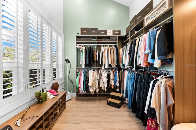 spacious closet featuring a towering ceiling and light hardwood / wood-style flooring