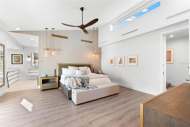 bedroom featuring ceiling fan, a towering ceiling, connected bathroom, and light hardwood / wood-style floors