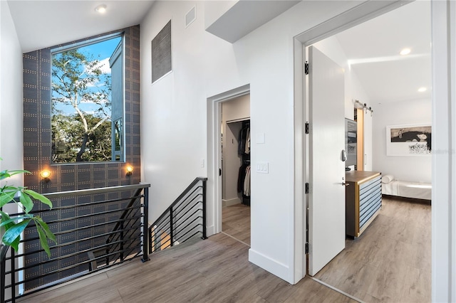 hall with a barn door and light wood-type flooring