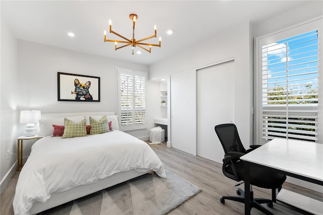 bedroom with a chandelier, light wood-type flooring, and a closet