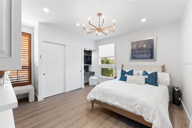 bedroom featuring an inviting chandelier, light wood-type flooring, and a closet