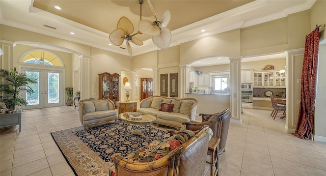 living room with light tile patterned floors, a tray ceiling, ornamental molding, french doors, and ornate columns