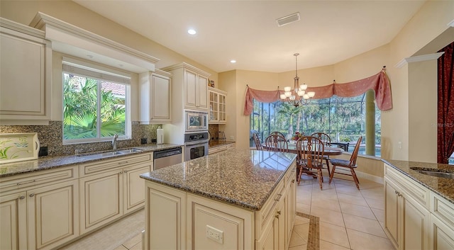 kitchen with a center island, hanging light fixtures, cream cabinetry, and appliances with stainless steel finishes