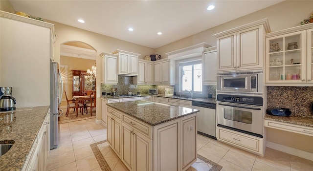 kitchen featuring sink, a kitchen island, stone counters, and appliances with stainless steel finishes