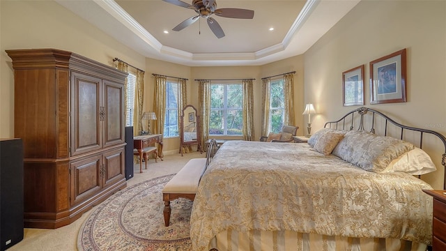 bedroom featuring light carpet, ornamental molding, a raised ceiling, and ceiling fan