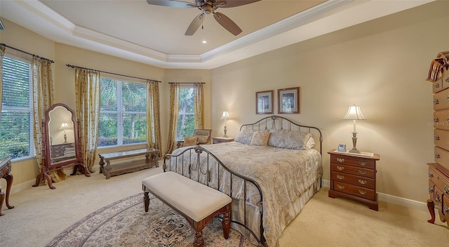 bedroom featuring ornamental molding, light colored carpet, ceiling fan, and a tray ceiling