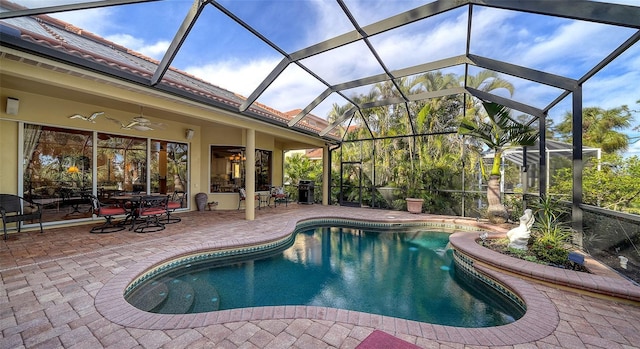 view of pool featuring ceiling fan, area for grilling, glass enclosure, and a patio area