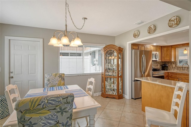 tiled dining area with a healthy amount of sunlight, sink, and a chandelier