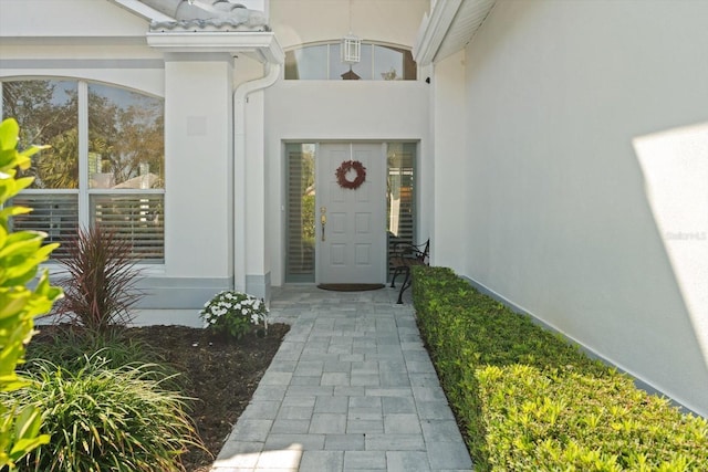 doorway to property featuring a tiled roof and stucco siding