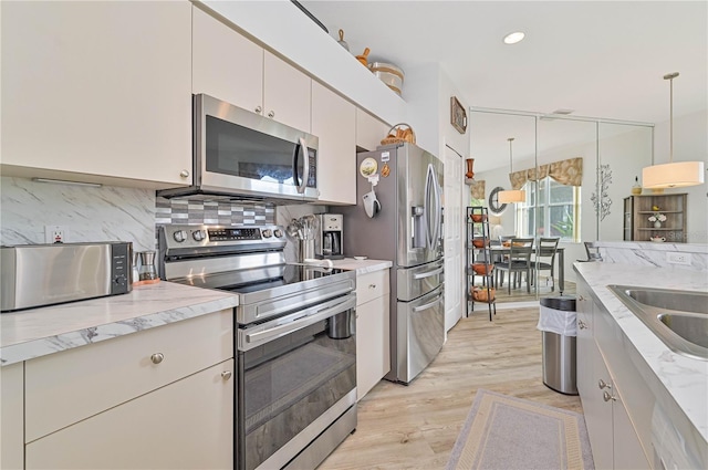 kitchen featuring pendant lighting, sink, backsplash, stainless steel appliances, and light stone counters