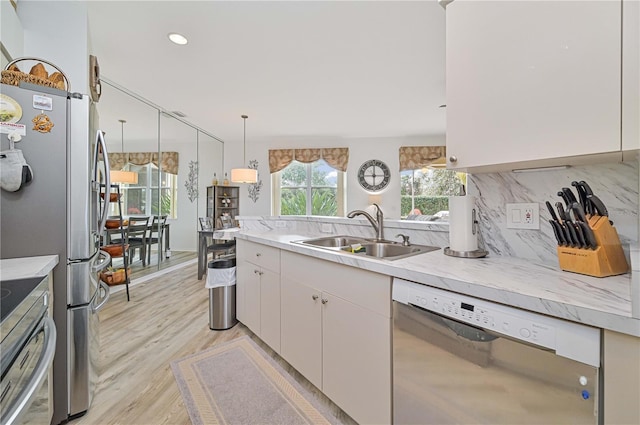 kitchen with sink, white cabinetry, decorative light fixtures, stainless steel appliances, and decorative backsplash