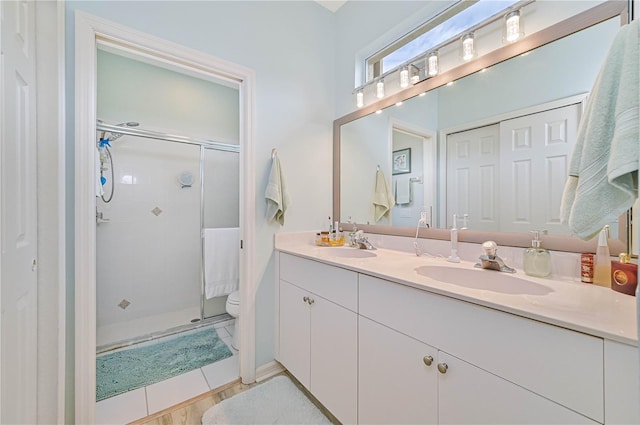 bathroom with vanity, a shower with door, and toilet