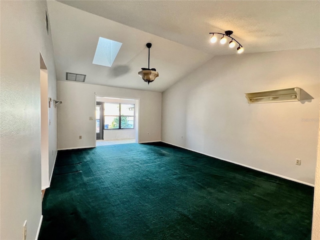 spare room featuring lofted ceiling with skylight and dark colored carpet