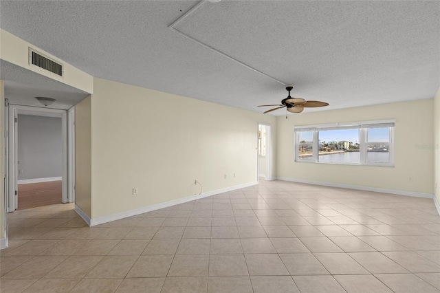 empty room featuring light tile patterned flooring, ceiling fan, and a textured ceiling