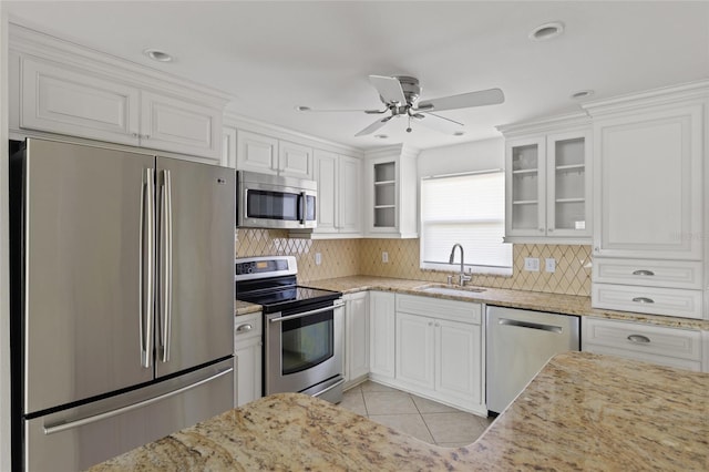 kitchen with appliances with stainless steel finishes, tasteful backsplash, white cabinetry, sink, and light tile patterned floors