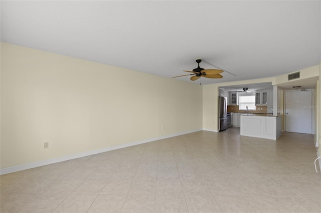 unfurnished living room featuring ceiling fan and sink