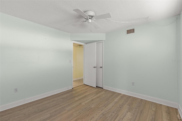 spare room with ceiling fan, light hardwood / wood-style flooring, and a textured ceiling