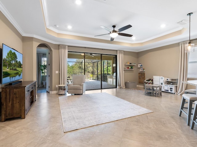 living room with light tile patterned floors, a tray ceiling, ornamental molding, and ceiling fan