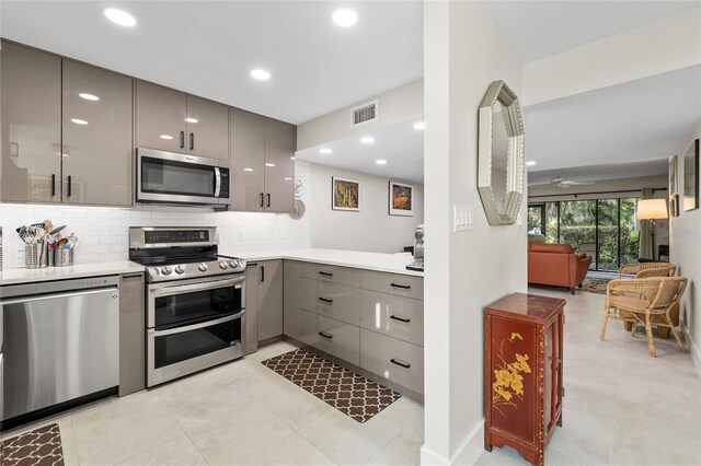 kitchen featuring gray cabinets, light tile patterned flooring, appliances with stainless steel finishes, and decorative backsplash