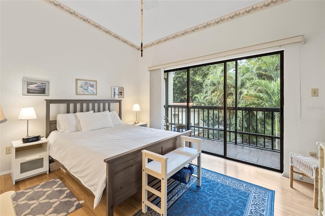 bedroom featuring a towering ceiling, access to exterior, and light wood-type flooring