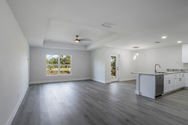 kitchen with sink, decorative light fixtures, stainless steel dishwasher, a tray ceiling, and white cabinets