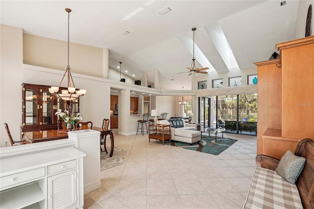 living room featuring a skylight, ceiling fan with notable chandelier, high vaulted ceiling, and light tile patterned floors