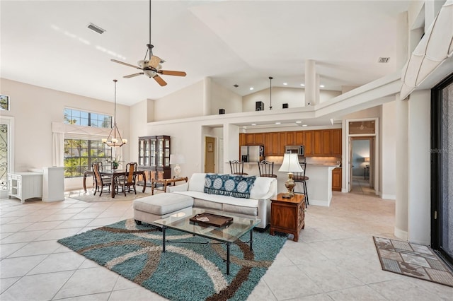 living room with ceiling fan with notable chandelier, light tile patterned floors, and high vaulted ceiling