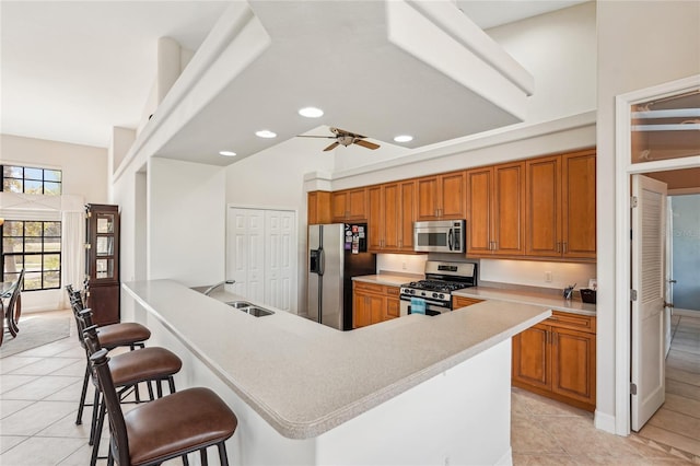 kitchen with sink, light tile patterned floors, a breakfast bar area, and appliances with stainless steel finishes