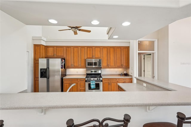 kitchen with ceiling fan, stainless steel appliances, a kitchen breakfast bar, and kitchen peninsula