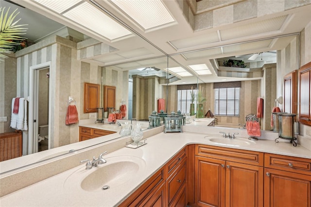 bathroom with a skylight, vanity, and toilet