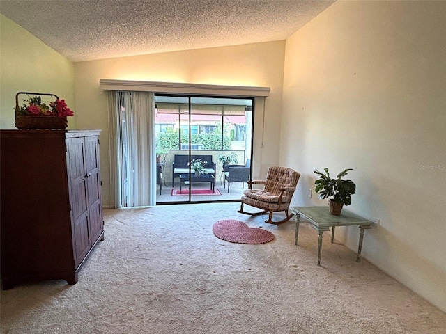 sitting room with lofted ceiling, light carpet, and a textured ceiling