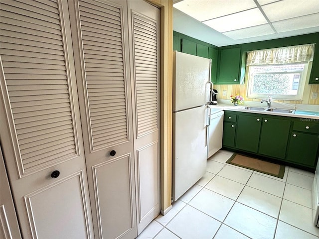 kitchen featuring sink, green cabinets, white appliances, and light tile patterned floors