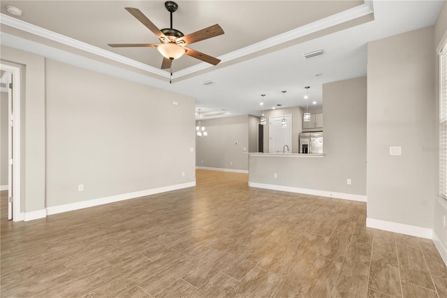 unfurnished living room featuring crown molding, light hardwood / wood-style flooring, and a tray ceiling