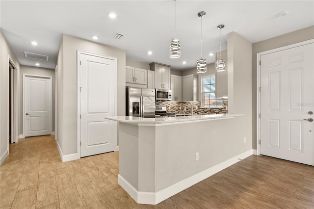 kitchen with decorative light fixtures, sink, decorative backsplash, kitchen peninsula, and stainless steel appliances