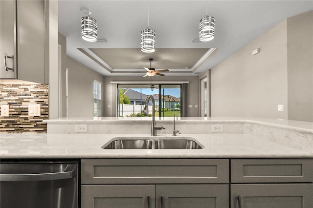 kitchen with sink, light stone counters, gray cabinets, dishwasher, and a raised ceiling