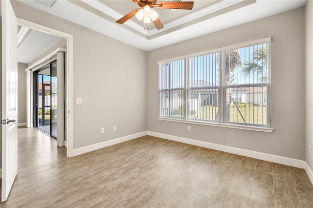 spare room featuring a tray ceiling, light hardwood / wood-style floors, and ceiling fan