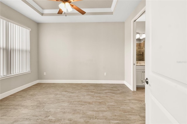 empty room with crown molding, a raised ceiling, and ceiling fan