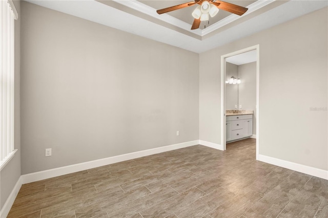 unfurnished bedroom with ceiling fan, ensuite bath, a raised ceiling, and light hardwood / wood-style floors