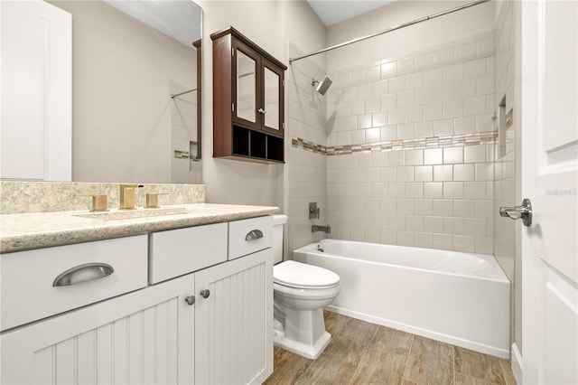 full bathroom featuring vanity, tiled shower / bath, hardwood / wood-style floors, and toilet