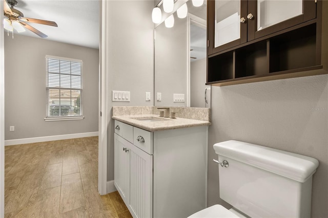 bathroom with hardwood / wood-style flooring, vanity, ceiling fan, and toilet