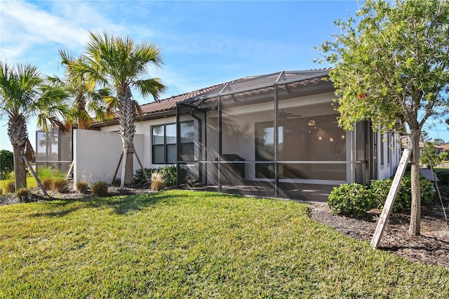 back of property with ceiling fan, a lanai, and a lawn