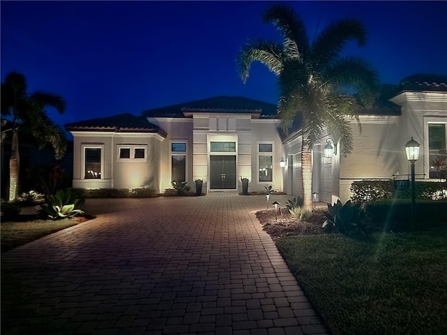 view of front of property featuring a tiled roof, driveway, and stucco siding