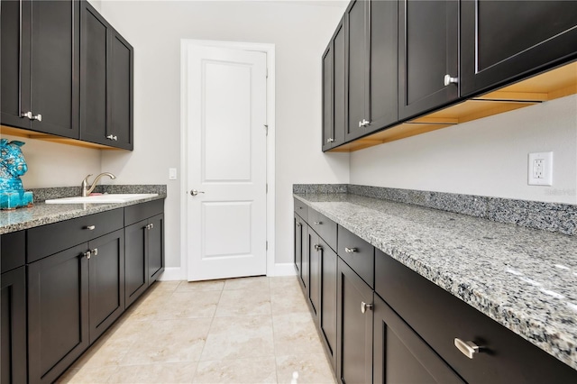 laundry area featuring light tile patterned flooring, a sink, and baseboards
