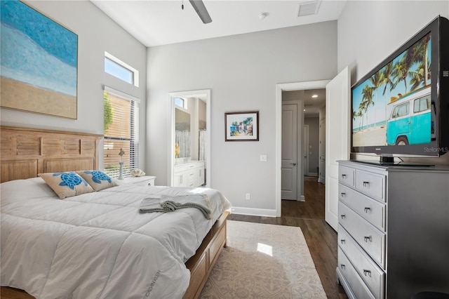 bedroom featuring ensuite bathroom, dark wood-type flooring, visible vents, a high ceiling, and baseboards