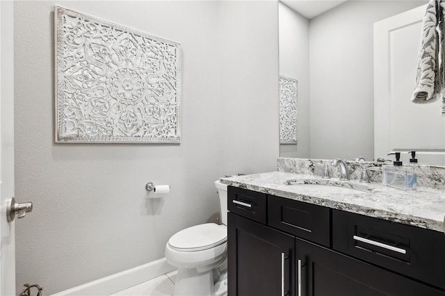 half bathroom featuring toilet, vanity, and baseboards
