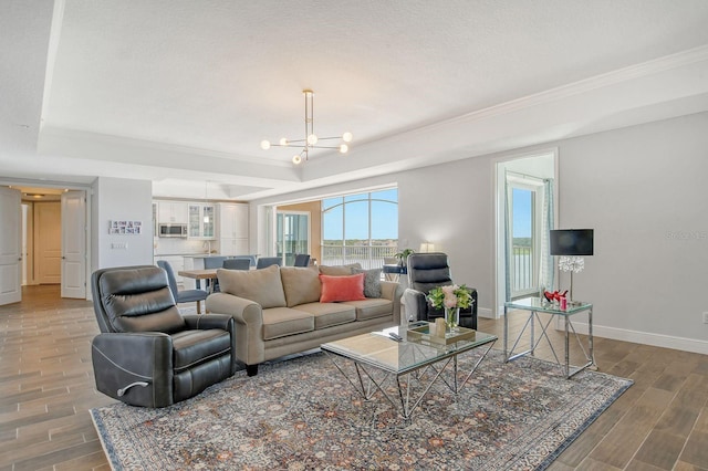 living room featuring a chandelier, a textured ceiling, wood finish floors, baseboards, and a tray ceiling