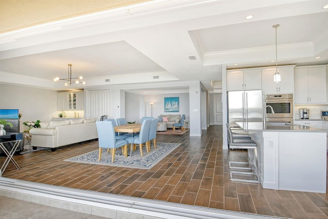 dining room featuring a chandelier, recessed lighting, wood tiled floor, a raised ceiling, and crown molding