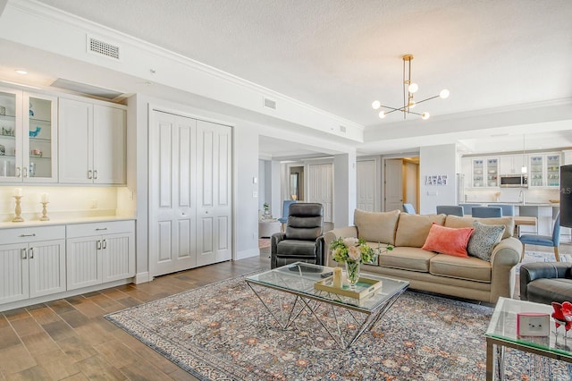 living room with a chandelier, ornamental molding, a textured ceiling, and wood finished floors